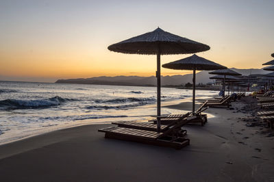 Lifeguard hut on beach against sky during sunset