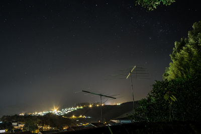 Antenna on rooftops of houses against star field at night