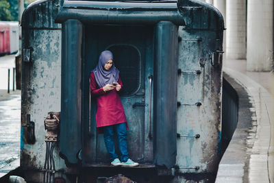 Young woman using smart phone while standing on train