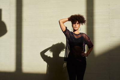 Portrait of young woman standing against wall