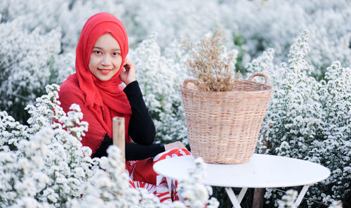 Portrait of smiling woman with red flowers in snow