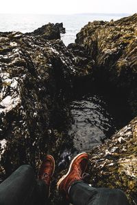 Low section of man standing on rock by water