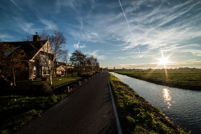 Road by canal against sky