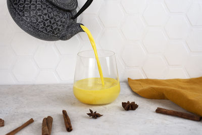 Golden moon milk with turmeric is poured from teapot into a glass. healthy detox drink.