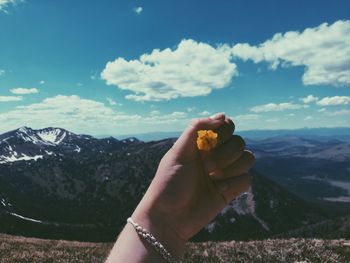 Close-up of hand holding mountain against sky