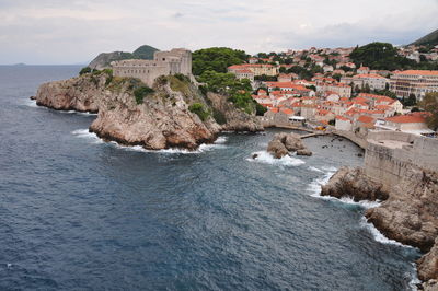 Buildings by sea against sky