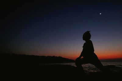 Silhouette of woman standing at sunset