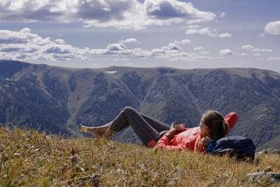 Woman lying on field against mountain