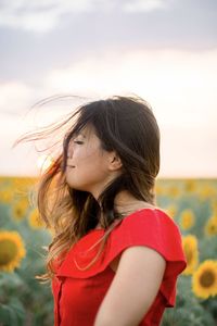 Portrait of girl on a sunflower field and air blowing her hair 