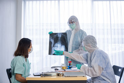 Rear view of people working on table