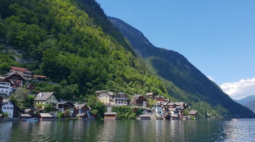 Scenic view of lake by buildings and mountains against sky