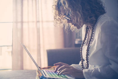 Side view of woman using laptop at home