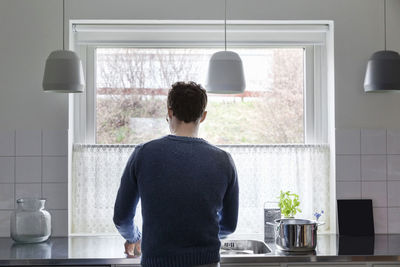 Rear view of man working in kitchen at home