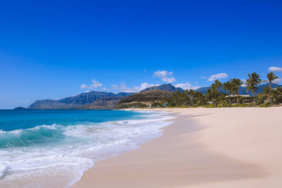 Scenic view of beach against blue sky