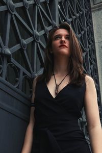 Beautiful young woman standing by metal door