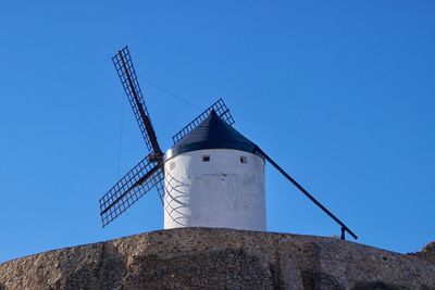 Low angle view of traditional windmill against clear blue sky