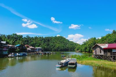 Boats moored on lake by buildings against sky