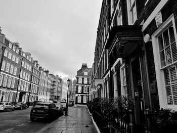 Cars on street in city against sky