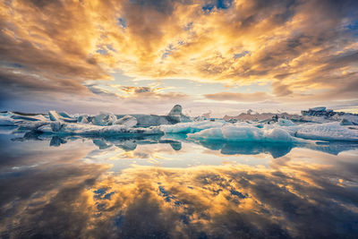 Frozen lake against cloudy sky during sunset