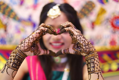 Smiling bride with henna tattoo making heart shape