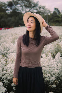 Rear view of woman wearing hat standing on field