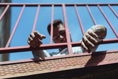 Low angle view of man seen through railing