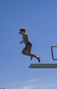 Low angle view of boy jumping off platform