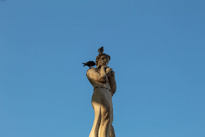 Low angle view of statue against clear blue sky