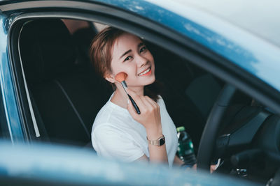 Portrait of woman applying make-up in car