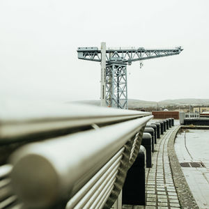 Metallic structure by bridge against sky