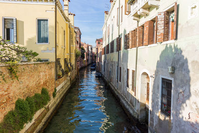 Canal amidst buildings in city against sky