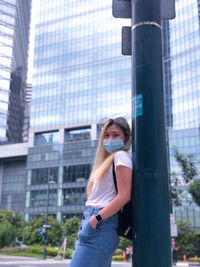 Portrait of young woman standing against building in city