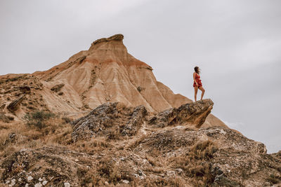 Low angle view of woman on rock against sky