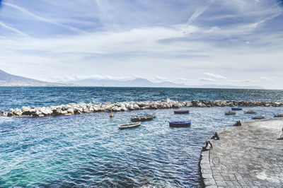 Boats moored at calm blue sea against sky