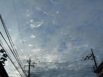 Low angle view of electricity pylon against cloudy sky