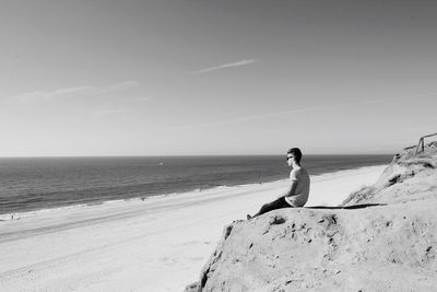 Woman standing on beach against clear sky