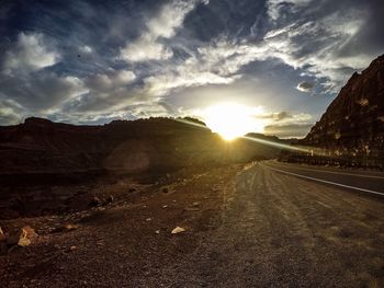 Road by mountains against sky during sunset
