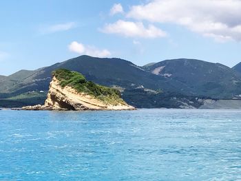 Scenic view of sea and mountains against blue sky