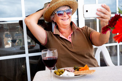 Smiling senior woman taking selfie at table