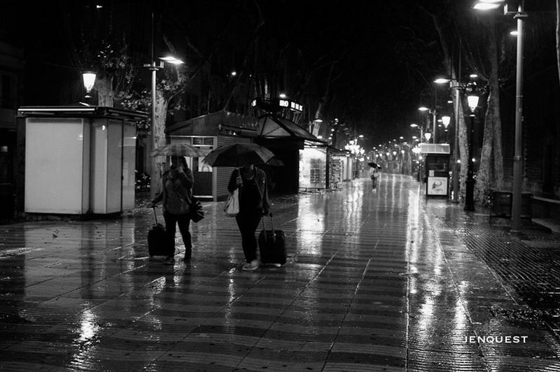 illuminated, night, architecture, built structure, building exterior, lighting equipment, street light, street, the way forward, city, walking, building, wet, men, incidental people, city life, reflection, lifestyles, full length