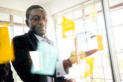 Businessman holding adhesive notes on glass