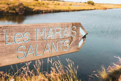 Wooden sign indicating the direction of the salt marshes marais salants in front of a sea water sea