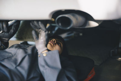 Female mechanic examining under car at auto repair shop