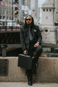 Full length of hippie businessman leaning on railing in city
