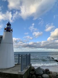 Lighthouse by sea against sky