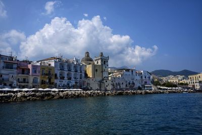 Buildings by sea against blue sky