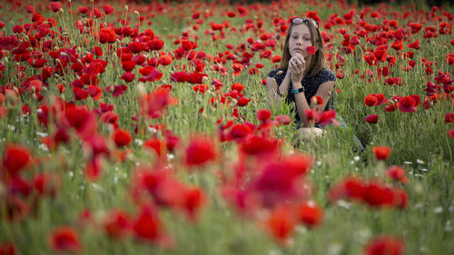 Woman sitting on poppy flowers at field