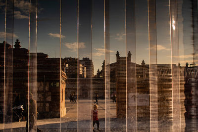 Digital composite image of silhouette buildings against sky seen through glass window