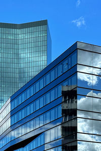 Low angle view of modern office buildings against blue sky