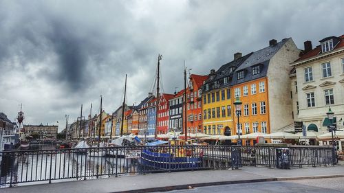 Boats moored at harbor against cloudy sky